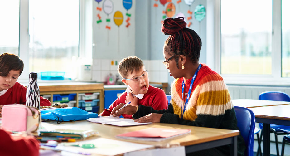 Teacher with young pupil in classroom