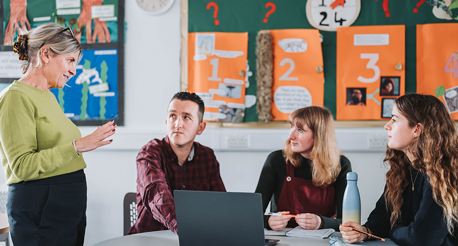 Lecturer with three students in a classrooom